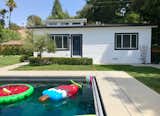 Villa prefab prefabricated ADU small home with fiber cement lap siding, asphalt gable roof, and clerestory windows in California backyard beside pool with inflatable floaties.