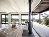 Living room of Connect Homes prefab prefabricated Designer Series home house in Santa Ynez, California, with wood burning stove, covered wood deck, floor-to-ceiling glass sliding windows, and Eames arm chair.