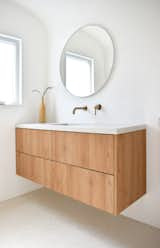 The bathroom features a custom concrete sink from Caesarstone and a vanity base from Ikea accented with customized panels.