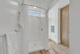 White shower booth with ceramic tiling Single Family Home prefab ADU by Bequall.