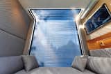 Sleeping alcove of of microHaus prefab ADU tiny home by Haus.me with grey upholstery and blue sliding curtain covering floor-to-ceiling window.