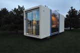 MicroHaus prefab ADU tiny home by Haus.me sits in field glade at dusk.