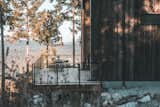 Cedar-sided, glulam prefab prefabricated home by Blend Projects with large deck with glass-paneled railing sits on hillside in British Columbia, Canada.