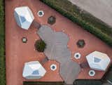 Bird's-eye view of group of three aluminum-clad  prefab prefabricated Cyber pebble pod outdoor workstation by Hello Wood arranged around wood deck.