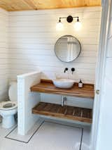 For the primary bathroom floor, Bloom used a glossy white penny tile with a black penny tile border.