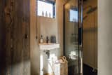 Bathrooms of Konga M model cabin prefab prefabricated slim CLT cross-laminated timber cabin with concrete walls and glass enclosed shower booth.