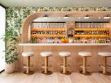 bar stools sit in front of a curved bar arch and wallpaper