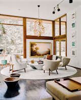 In the living room, soft-hued seating arranged in a circle is perfect for entertaining. On the far wall, Sunrise Over the Hudson, by Erik Koeppel, competes with the stunning scenery outside. “Charlie was interested in skewered views, like looking straight up at the sky and then out to the woods,” says Rick.