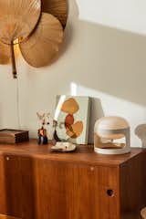 Detail of vintage white table lamp on medium toned wood credenza console table dresser with small decorative vases, ceramic, wood box, and abstract minimal painting in prefab home in Harpswell, Maine, renovated by Home Union midcentury furniture store in Brooklyn.