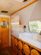 The trailer's original twin bed now serves as a reading nook with sliding polycarbonate partitions. For storage, the couple created cubbies for milk crates fixed with wood cutouts.