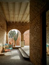 Cloister, colonnade, brick porch, logia, gallery paved in grey stone and bordered in arched brick walls and wood ceiling wraps an 1800s brick structure in Todos Santos, Baja California, Mexico, renovated and expanded by Ernesto Kut Gomez, Ellen Odegaard, and Yashar Yektajo.
