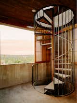 Spiraling black metal staircase rises through concrete tower added to 1800s brick structure in Todos Santos, Baja California, Mexico, renovated and expanded by Ernesto Kut Gomez, Ellen Odegaard, and Yashar Yektajo.
