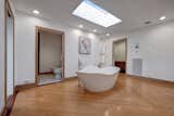 In the primary bath, a large soaking tub sits beneath a skylight.