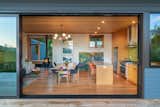 Combined kitchen, dining, and living room seen past a floor-to-ceiling glass sliding door in prefab prefabricated house, home, residence designed by Make Ground Design and built by Method Homes on Orcas Islands, in the San Juan Islands of British Columbia, Washington.