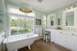 A vintage soaking tub in the primary bathroom overlooks the lush backyard.