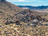 A Joshua Tree-lined driveway leads to the remote home, nestled among historic boulders.