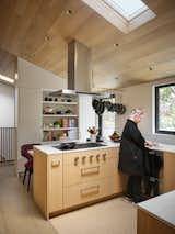The kitchen is customized for Roberta, an avid cook. Easy-to-reach pots hang from a custom rack by Bjørn Design. Its hooks can be lengthened if she has to reach from a wheelchair someday; a lowered counter where she likes to work, read, and play cards can accommodate a wheelchair, should she need one. Oak veneers for the ceilings, floors, and cabinetry were a splurge, but Roberta loves their warmth and texture.
