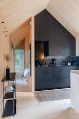 Kabn prefab prefabricated off-grid, boutique retreat cabin holiday stay tiny home on the shores of Loch Fyne, Scotland, with light wood CLT cross laminated interior walls and floors, pitched exposed ceiling, and kitchen with black millwork cabinetry.