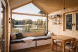 Interior living room dining room of tiny home micro home LOVT in Germany with sectional bench daybed reading nook, medium-toned hard wood floors, spruce walls, and pitched roof.