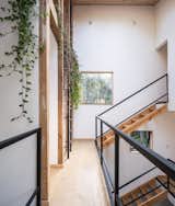 Hallway catwalk of staircase with light wood tread and floors, black metal railing, and white walls in home outside Puerto Varas, Chile, designed by Camilo Fuentealba and Eduardo Díaz of Estudio Sur.