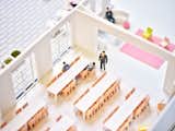 Close up of architecture model of tables, chairs, and people within a large room of building made by sisters Anda and Jenny French of Boston-based architecture firm French 2D.