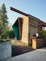 Wood slats clad side of accessory dwelling unit ADU with protruding, angled awning entryway in St. Helena, California CA designed by Ryan and Maddie Chandler of Chandler Workshop Architects.