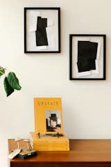 A stack of books titled upstate with yellow covers sits below black and white abstract geometric artwork framed in black in Ninze Chen ‘s vintage furniture store Long Weekend in Livingston Manor, Catskills, New York NY.