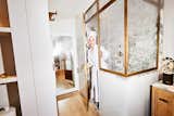 Designer Analisse Taft-Gersten leaves enclosed shower booth with marble finishes wearing white robe in bathroom with medium toned wood flooring.
