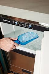 Woman scoops ice out of Scotsman Brilliance Nugget Ice Machine Model SCN60 with plastic blue scoop.