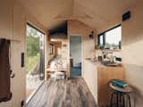 Interior of Norske Mikrohus tiny house micro house rast adu accessory dwelling unit prefab prefabricated in Norway with birch veneer walls, birch veneer ceiling, vinyl floors, lofted bed with ladder, stacked beds, bunk bed, and floor to ceiling glass folding door window.