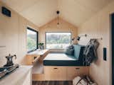Interior of Norske Mikrohus tiny house micro house rast adu accessory dwelling unit prefab prefabricated in Norway with birch veneer walls, birch veneer ceiling, vinyl floors, and built-in daybed sofa bench with storage.