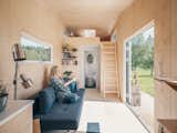 Interior of Norske Mikrohus tiny house micro house tind adu accessory dwelling unit prefab prefabricated in Norway with birch veneer walls, birch veneer ceiling, birch veneer floors, lofted bedroom with ladder, and floor to ceiling glass folding door window.
