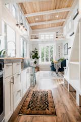 Interior of Paradise Tiny Home's Ohana Model with kitchen with concrete counter tops, bay window with ladder built into its side that leads up to a loft, and exposed pitched wooden beams in Hawaii Hawai'i.