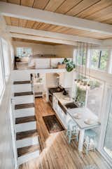 Interior of Paradise Tiny Home's Ohana Model with kitchen with concrete counter tops, staircase with dark wood tread leading up to bedroom loft, and exposed pitched wooden beams in Hawaii Hawai'i.