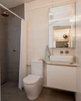 The bathroom has gray porcelain tiles for the floors and the walls in the shower. The toilet and sink are from Caroma Luna, and the fixtures are from Parisi.