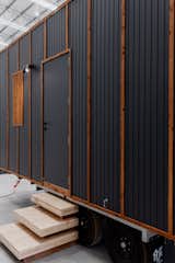 Plywood steps lead up to ROAM tiny mobile home on a three-axle trailer by Fabprefab with blackened Weathertex siding set in timber framing.