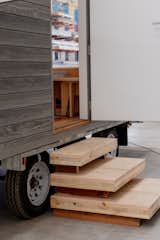 Plywood steps lead up to ROAM tiny mobile home on a three-axle trailer by Fabprefab with grey Accoya timber siding.