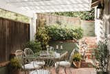 The fenced-in brick patio offers an idyllic setting for alfresco dining.
