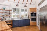 The bright and airy kitchen blends functionality and style, featuring a walk-in pantry, marble countertops, double wall ovens, and a concealed induction cooktop within a handmade butcher block island.