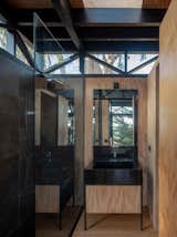 The same granite used to make the dining table also forms the bathroom sink. The walls are covered in plywood, and the floors are pine planks. The band of glass at the top wraps around the cabin.