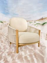 Softlands Outdoor Lounge Chair by Design Within Reach with light toned wood frame and beige cream cushions photographed against backdrop of white sand beach.