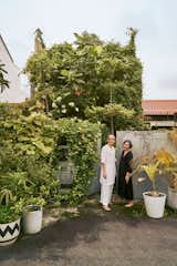 Minh Le Tien and Emylia Safian (left) stand at the gate to their unorthodox new home in Singapore. Designed by architect Ling Hao, the multilevel steel-and-concrete structure is wrapped in unbridled greenery and connects seamlessly with the outdoors.