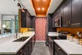 Patterned wallpaper brings a playful pop of color to the galley-style kitchen.
