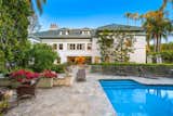 The private backyard presents a resort-like setting, complete with a sparkling pool, stone fountains, numerous patios, and a 1,000-square-foot guest house.