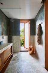“We value feeling over a perfect or manufactured finish,” says Kathryn, “so we jumped at anything touchy-feely, such as the droplet-like tiles cladding bathroom wing walls and structural columns that we are constantly petting.” Texture is at play everywhere, from a bathroom’s pebble-wash terrazzo floors that wrap up walls to the lush landscaping outside.