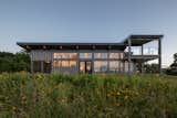 The front of the new build features a "watch tower" meant to mimic the form of the greenhouse and offer 360-degree views of the landscape. Wildflowers spread across the valley.