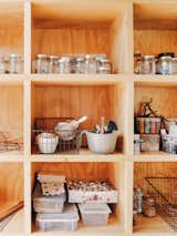 Arts tools and containers fill cubies in wall-to-wall millwork cabinetry in an art studio with arched curving roof built on a flatbed trailer in Salida, CO.