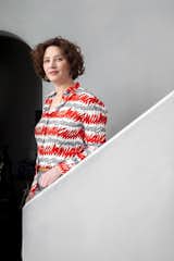 Woman stands on curving sculptural white staircase in a mixed-used building in Ghent, Belgium, designed by Jeremy Godenir, founder of MOEA Architectural Design Studio.