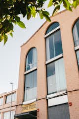 Exterior of a brick factory converted into an apartment by Gabriele Schiavon, creative director of Barcelona-based design studio Lagranja with tall arched windows.