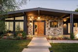 The front stone wall pops against the custom wooden entry door and sleek painted exterior.